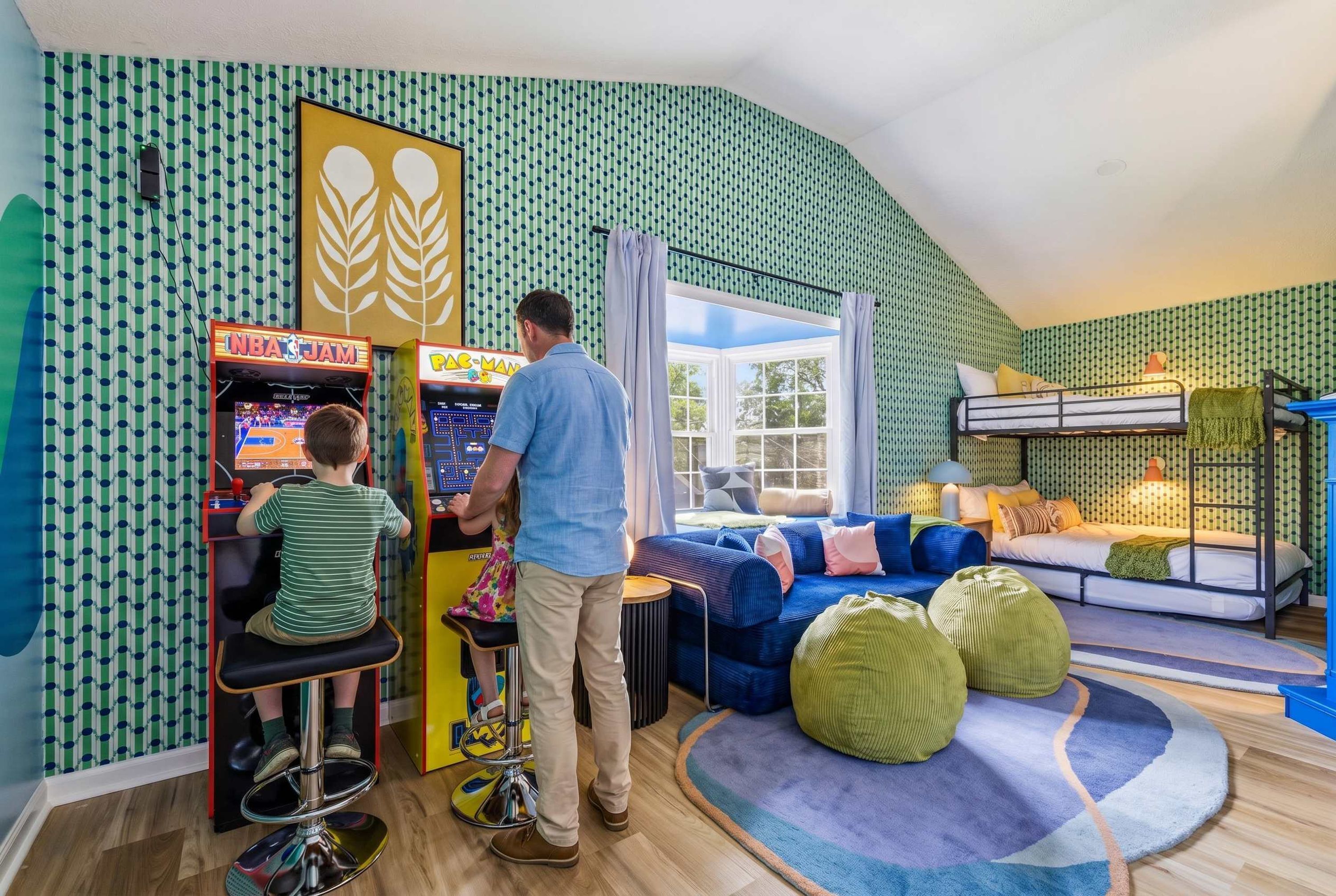 Una habitación con literas, juegos de arcade, un sofá y una ventana.