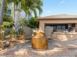 Eine Terrasse mit Feuerstelle, Sitzgelegenheiten im Freien und einem Poolbereich.