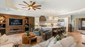 A modern living room with a sofa, coffee table, and a TV displaying 'Paradiso'. - Harbor Villa Waterfront Pool Spa Firepit (Indian Rocks Beach)