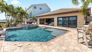 A swimming pool with a hot tub, lounge chairs, and a covered patio area. - Harbor Villa Waterfront Pool Spa Firepit (Indian Rocks Beach)