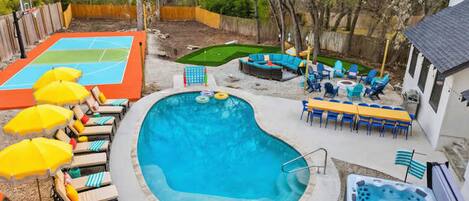 Un patio trasero con piscina, jacuzzi y zona de estar al aire libre.