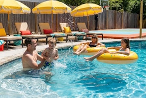 A swimming pool with inflatable rings, lounge chairs, and umbrellas. - Drive-in Dream - Theater - Pool - Pickleball (San Antonio)
