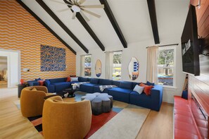 A modern living room with a sectional sofa, ottomans, and a ceiling fan. - Drive-in Dream - Theater - Pool - Pickleball (San Antonio)