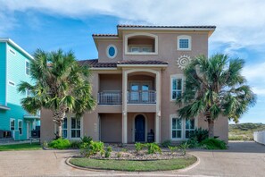 A two-story house with a balcony, a front door, and a small garden area. - Sunrise Beach Villa Beach Views Private Elevator (Port Aransas)