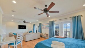A hotel room with a bed, a desk, a chair, a ceiling fan, and a TV. - Sunrise Beach Villa Beach Views Private Elevator (Port Aransas)