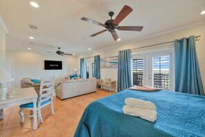 A hotel room with a bed, a desk, a chair, a ceiling fan, and a TV. - Sunrise Beach Villa Beach Views Private Elevator (Port Aransas)