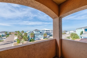 A balcony with a view of a residential area, including houses and a clear sky. - Sunrise Beach Villa Beach Views Private Elevator (Port Aransas)
