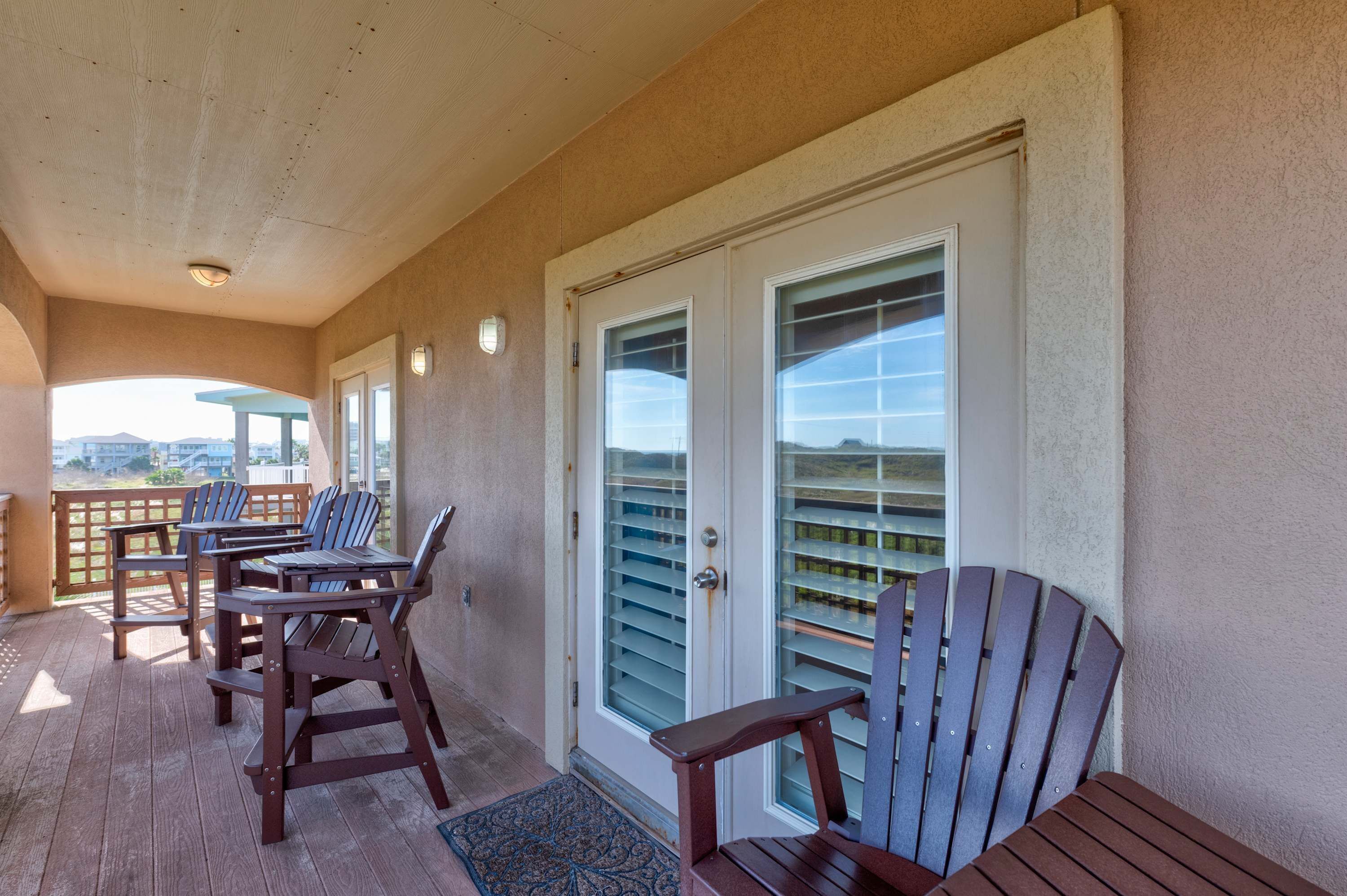 A covered outdoor area with wooden furniture and a door with glass panels.