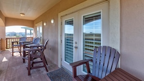A covered outdoor area with wooden furniture and a door with glass panels. - Sunrise Beach Villa Beach Views Private Elevator (Port Aransas)