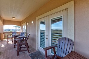 A covered outdoor area with wooden furniture and a door with glass panels. - Sunrise Beach Villa Beach Views Private Elevator (Port Aransas)