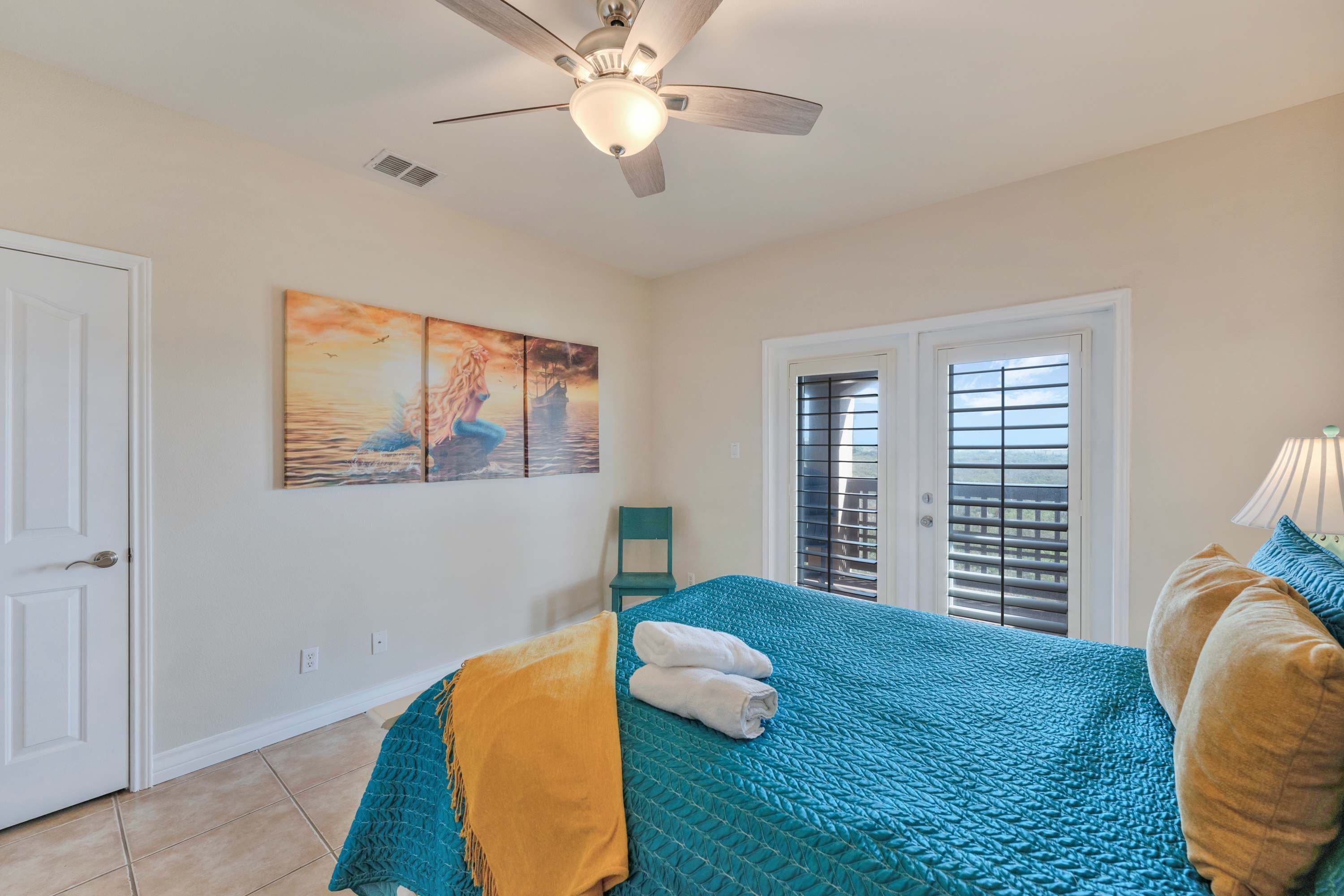 A bedroom with a bed, a ceiling fan, a window with blinds, and a painting on the wall.