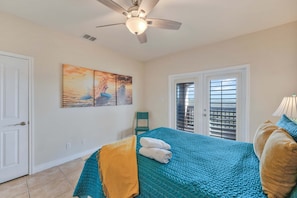 A bedroom with a bed, a ceiling fan, a window with blinds, and a painting on the wall. - Sunrise Beach Villa Beach Views Private Elevator (Port Aransas)