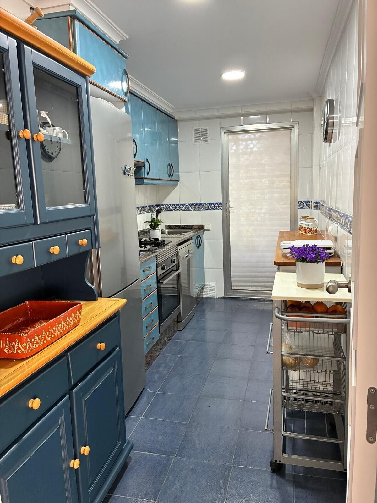 Une cuisine avec des meubles de couleur bleue, une cuisinière et un évier.