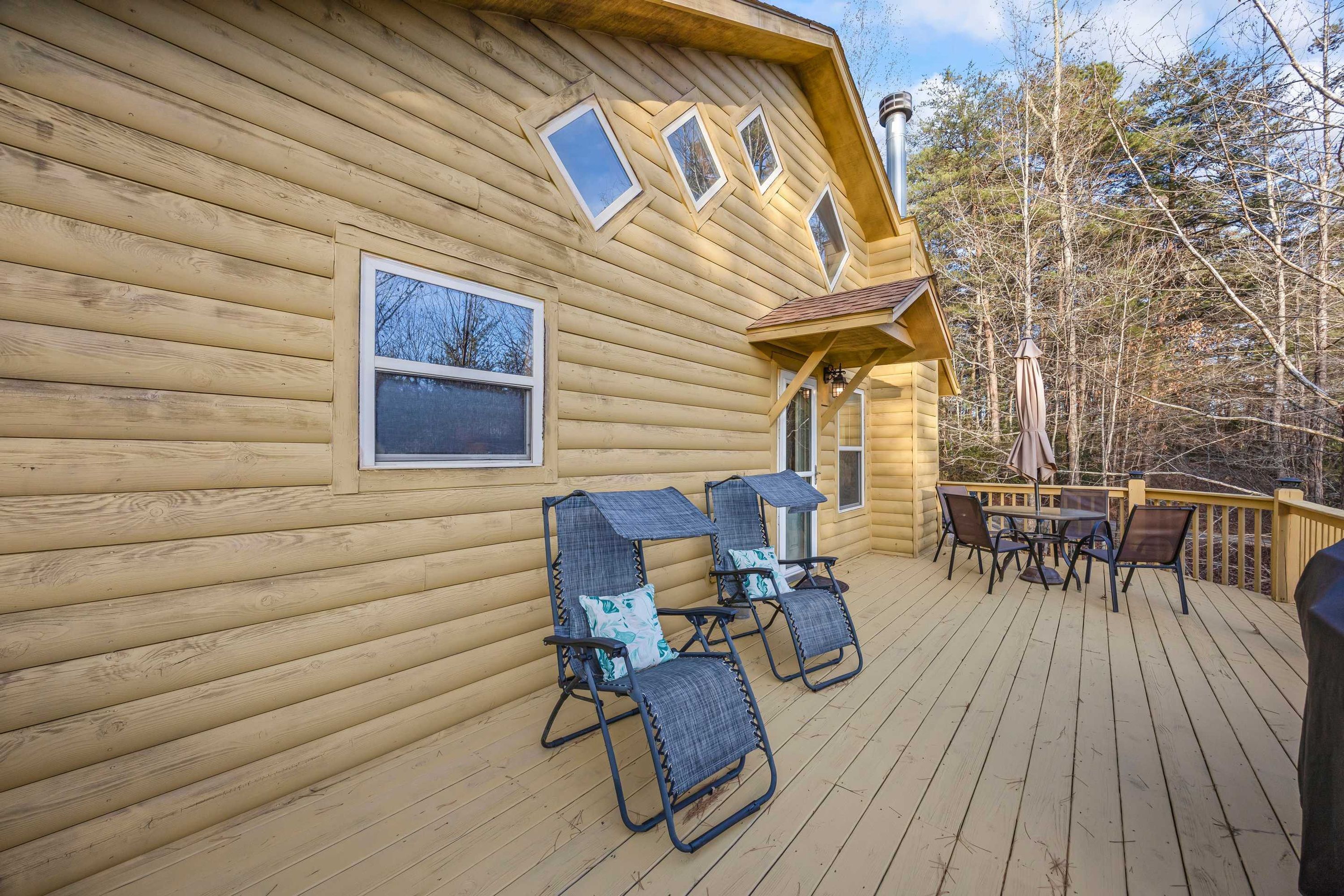 A wooden cabin with a deck, two chairs, and a table.