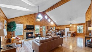 A spacious living area with a fireplace, a sofa, and a television labeled 'Home Team'. - Cozy Cabin in Mountains Firepit Views Games (Sautee Nacoochee)