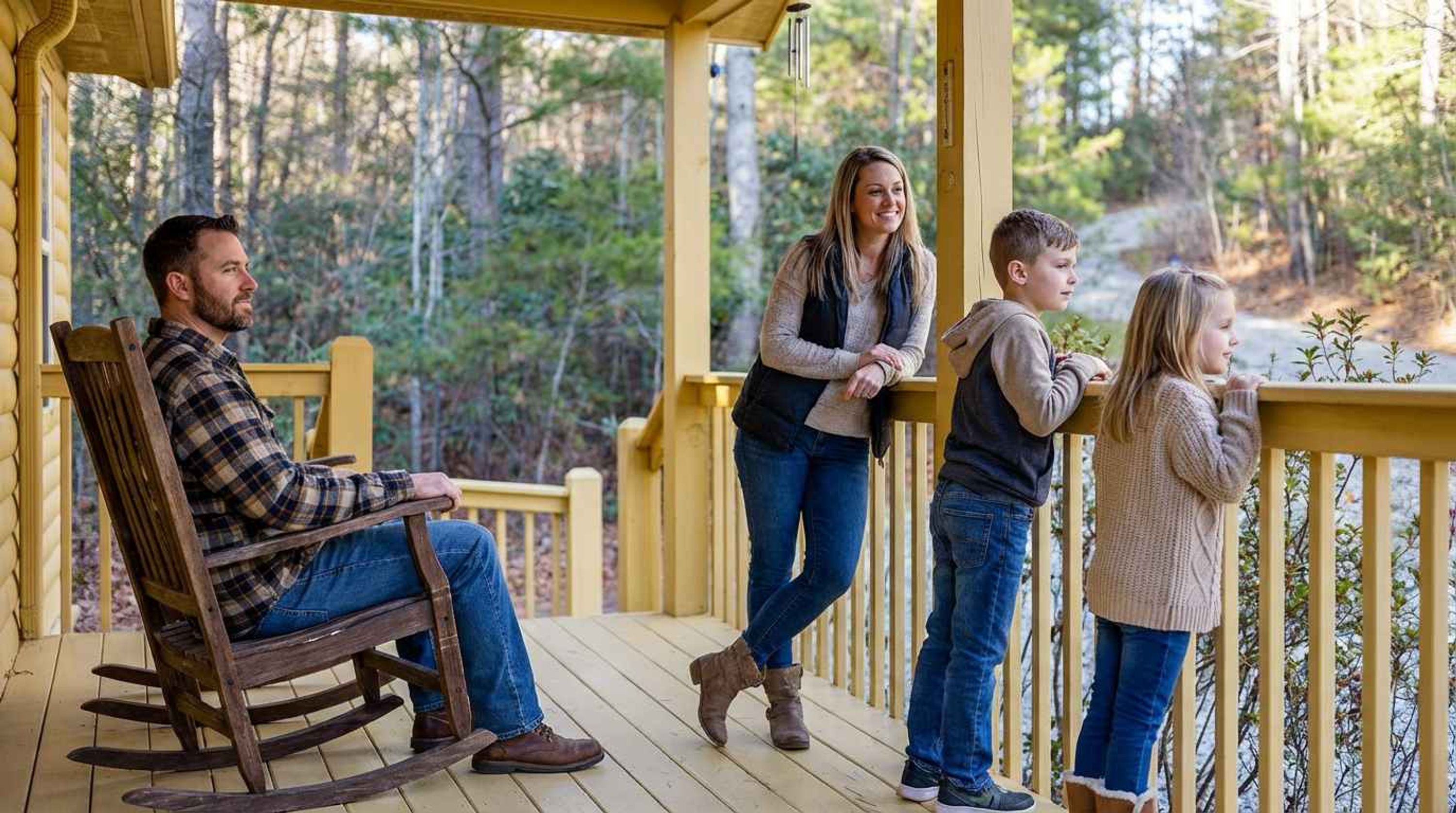 A family on a wooden deck with a forest backdrop.