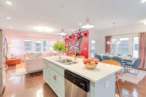 A modern kitchen with a central island, a dining area with blue chairs, and a living space with a pink sofa. - Butterfly BNB - Unforgettable Nashville Experience (Nashville)