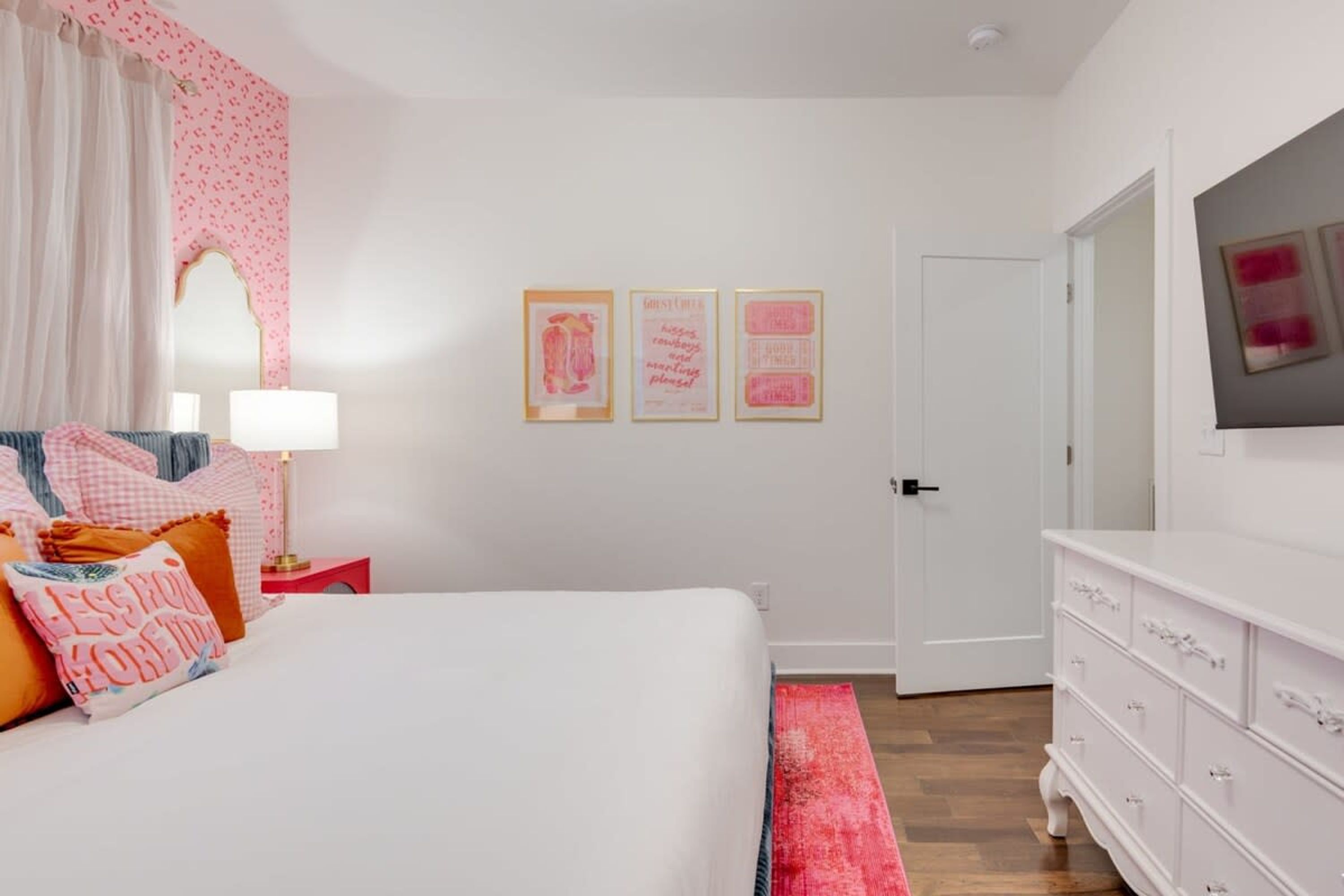 A bedroom with a bed, a dresser, a mirror, and three framed pictures on the wall.