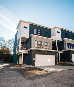 Um edifício residencial com vários andares, garagem, varanda e um pequeno alpendre.