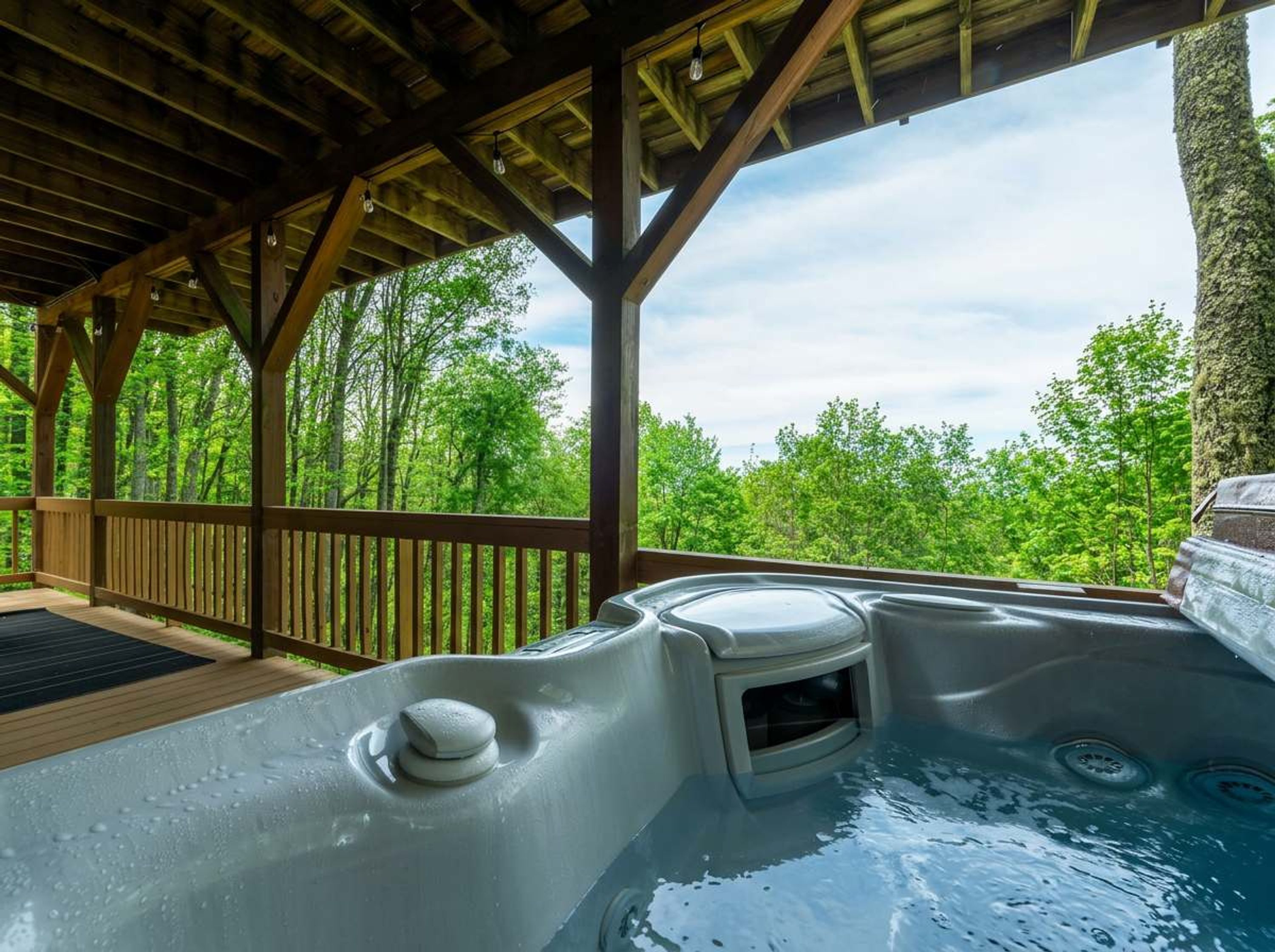 Ein Whirlpool unter einer Holzterrasse mit Blick auf einen Wald.