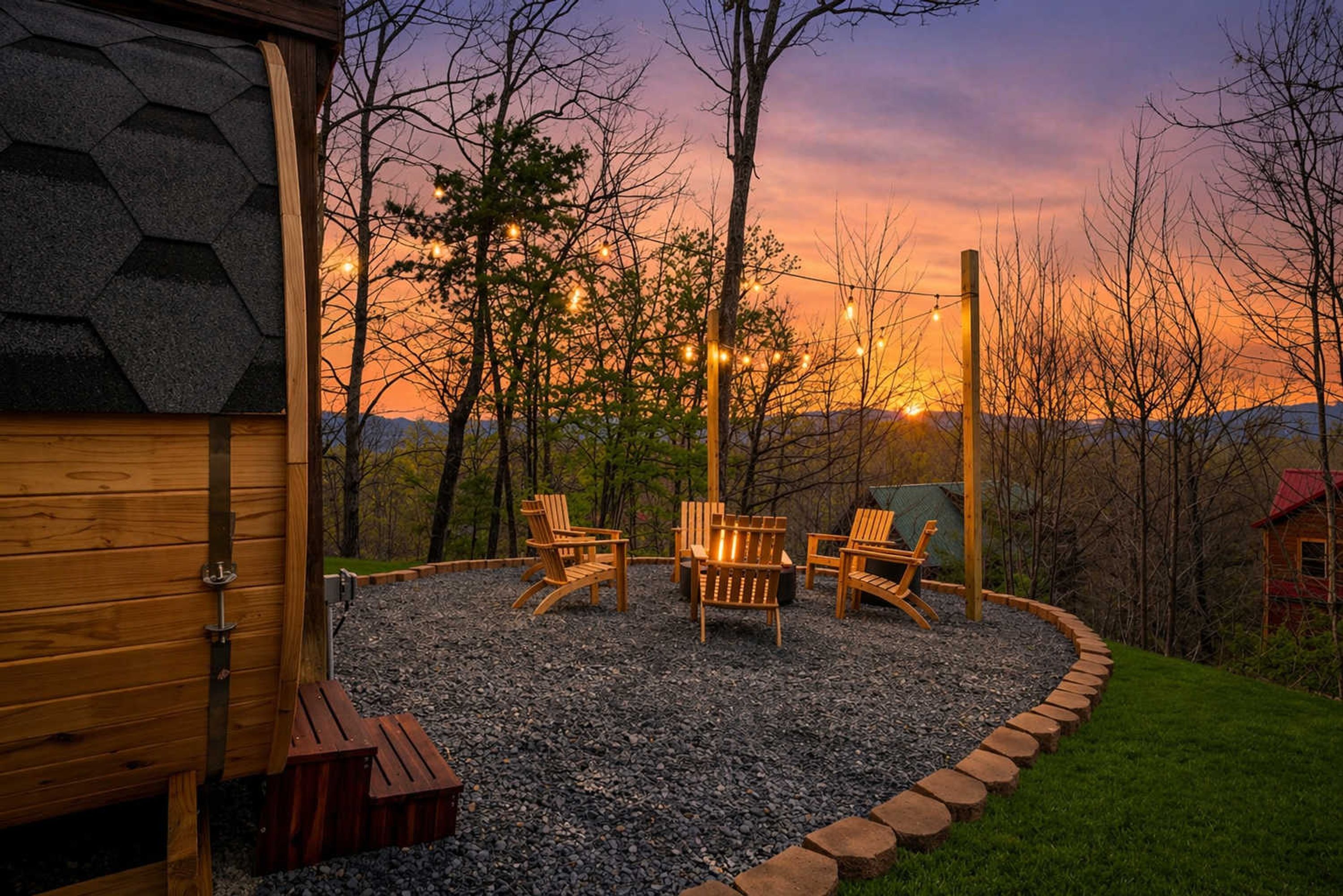 A wooden deck with Adirondack chairs and a fire pit, surrounded by a gravel area and a wooden fence.