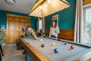 A pool table with balls in a room with wooden paneling and a large window. - Luxe Mountain Escape - Fire Pit - Hot Tub - Sauna (Sevierville)