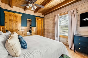 A wooden room with a bed, a dresser, a mirror, and a window with curtains. - Luxe Mountain Escape - Fire Pit - Hot Tub - Sauna (Sevierville)