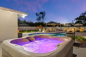 A hot tub with a pool, outdoor seating, and string lights. - Pastel Palms - Sport Court - Pool - Hot Tub - Bar (Bradenton)