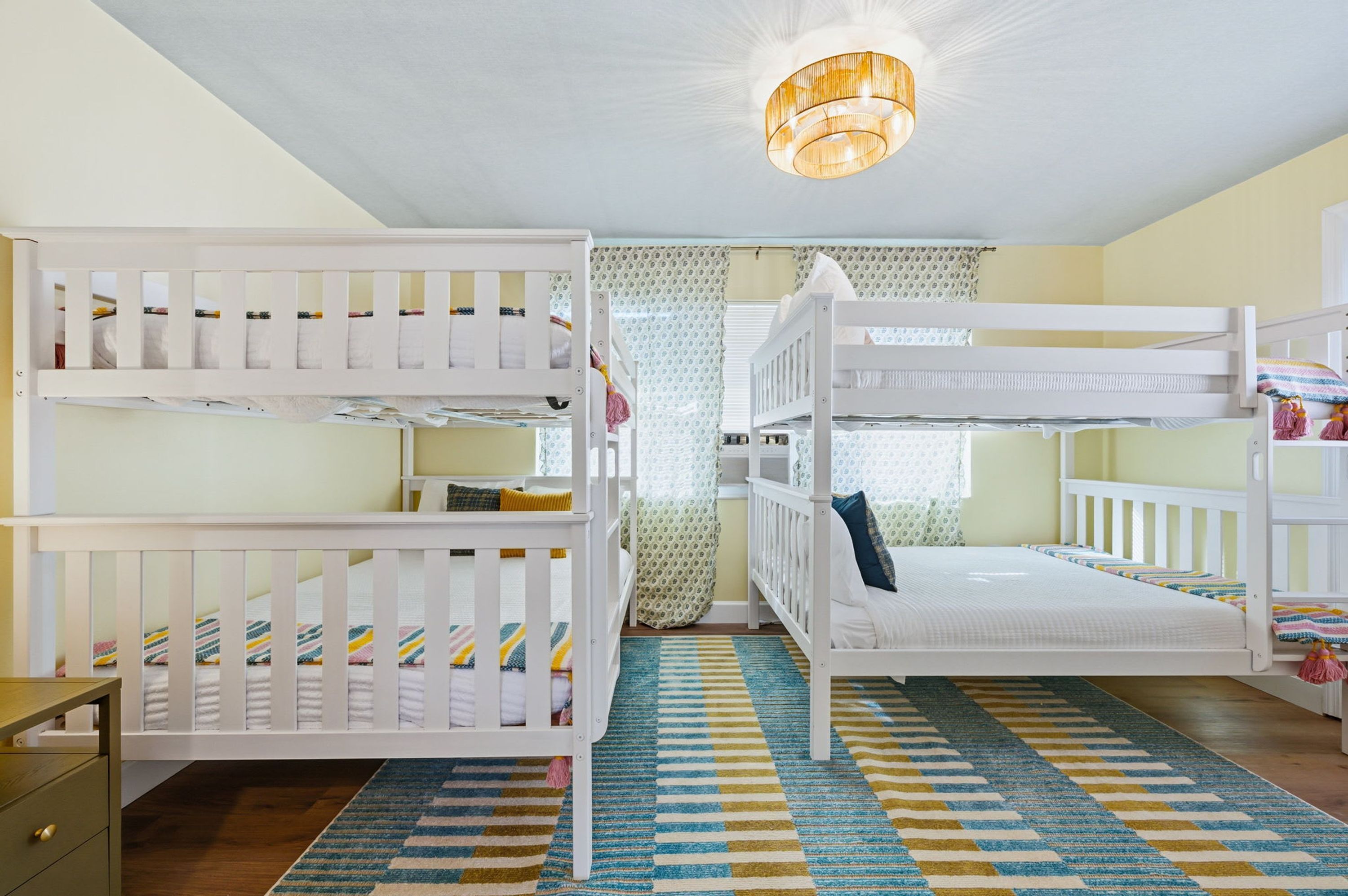A bunk bed room with a patterned rug and a ceiling light fixture.
