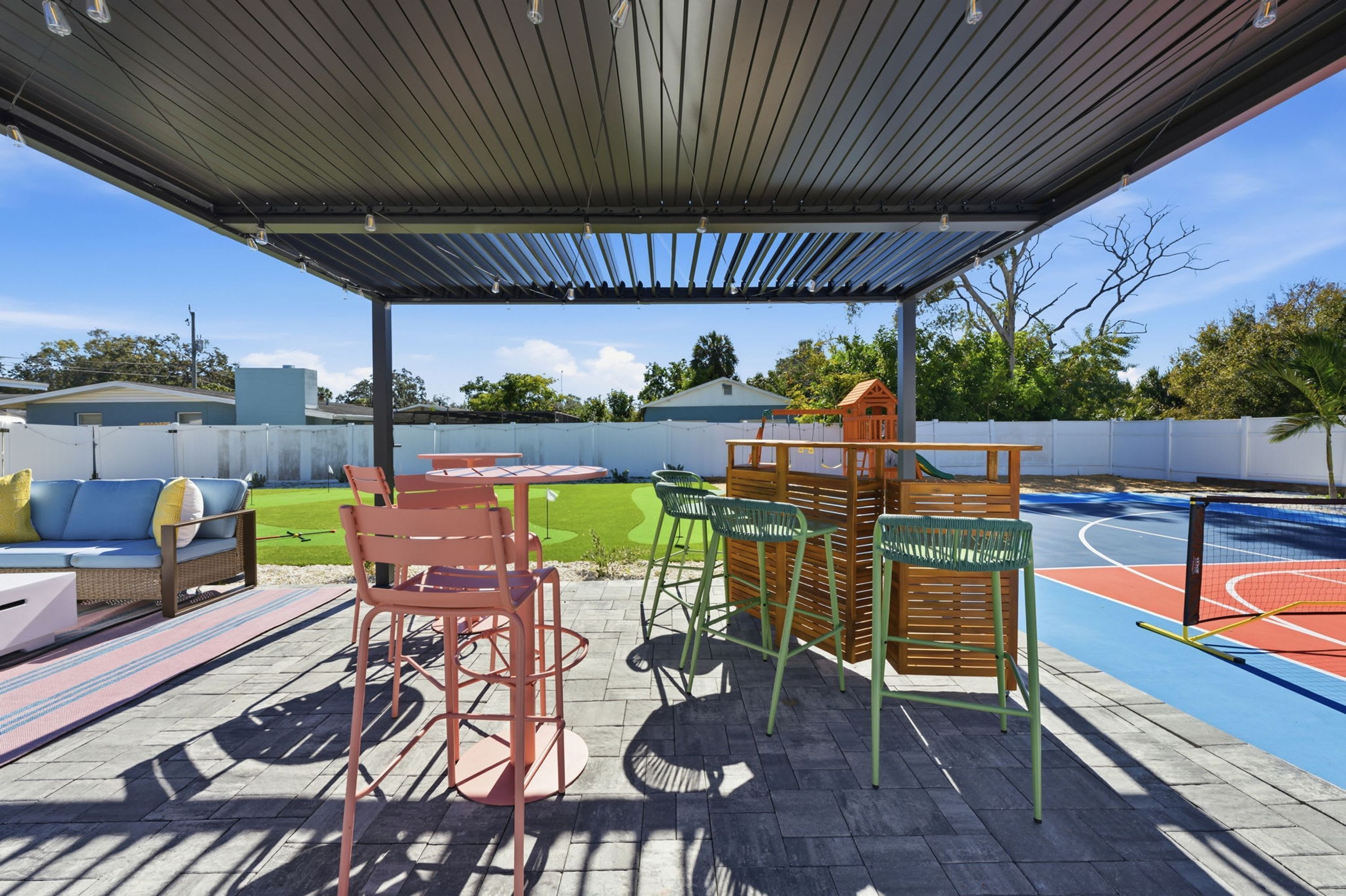 An outdoor patio with a covered seating area, a table, and chairs.