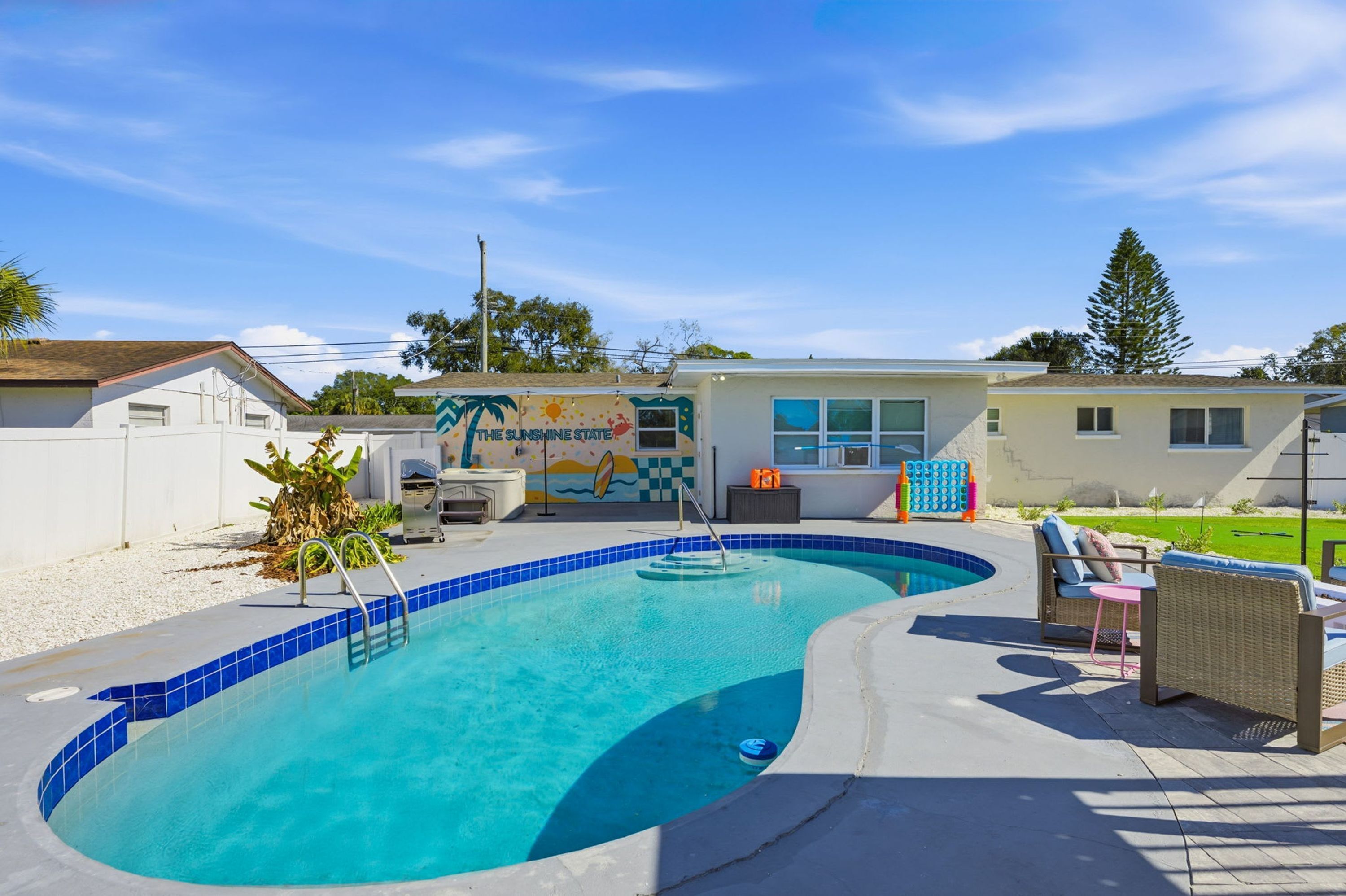 Une piscine au design incurvé, un jacuzzi et un espace de détente avec des meubles d’extérieur.