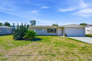 A single-story house with a garage, a well-maintained lawn, and a large cactus plant in the front yard. - Pastel Palms - Sport Court - Pool - Hot Tub - Bar (Bradenton)