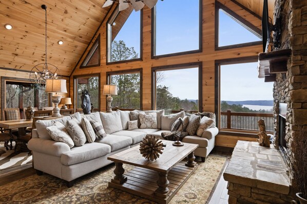 A spacious living room with a large sectional sofa, a wooden coffee table, and a stone fireplace. - Epic Mountain Views Hot Tub Games and Firepit (Ellijay)