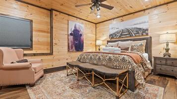 A cozy room with a bed, a chair, a bench, and a ceiling fan.