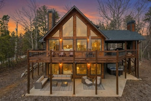 A two-story wooden cabin with a balcony, large windows, and outdoor seating. - Epic Mountain Views Hot Tub Games and Firepit (Ellijay)