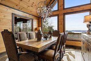 A wooden dining room with a chandelier, large windows, and a view of the outdoors. - Epic Mountain Views Hot Tub Games and Firepit (Ellijay)