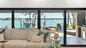 Ein modernes Wohnzimmer mit einem großen Fenster mit Blick auf einen Hafen und Wasser.