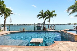 A swimming pool with a view of the water and palm trees. - Harbor Villa Waterfront Pool Spa Firepit (Indian Rocks Beach)