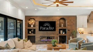 Ein modernes Wohnzimmer mit Kamin, einem an der Wand befestigten Schild mit der Aufschrift 'Paradiso' und einem Deckenventilator.