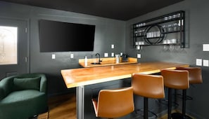 Eine moderne Küche mit einer Holzinsel, Barhocker, einem großen Flachbildfernseher und einem Weinkühlschrank.