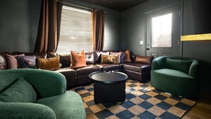 A living room with a sectional sofa, a green armchair, a coffee table, and a patterned rug. - Epic Family Getaway Speakeasy Pool Basketball (Glendale)