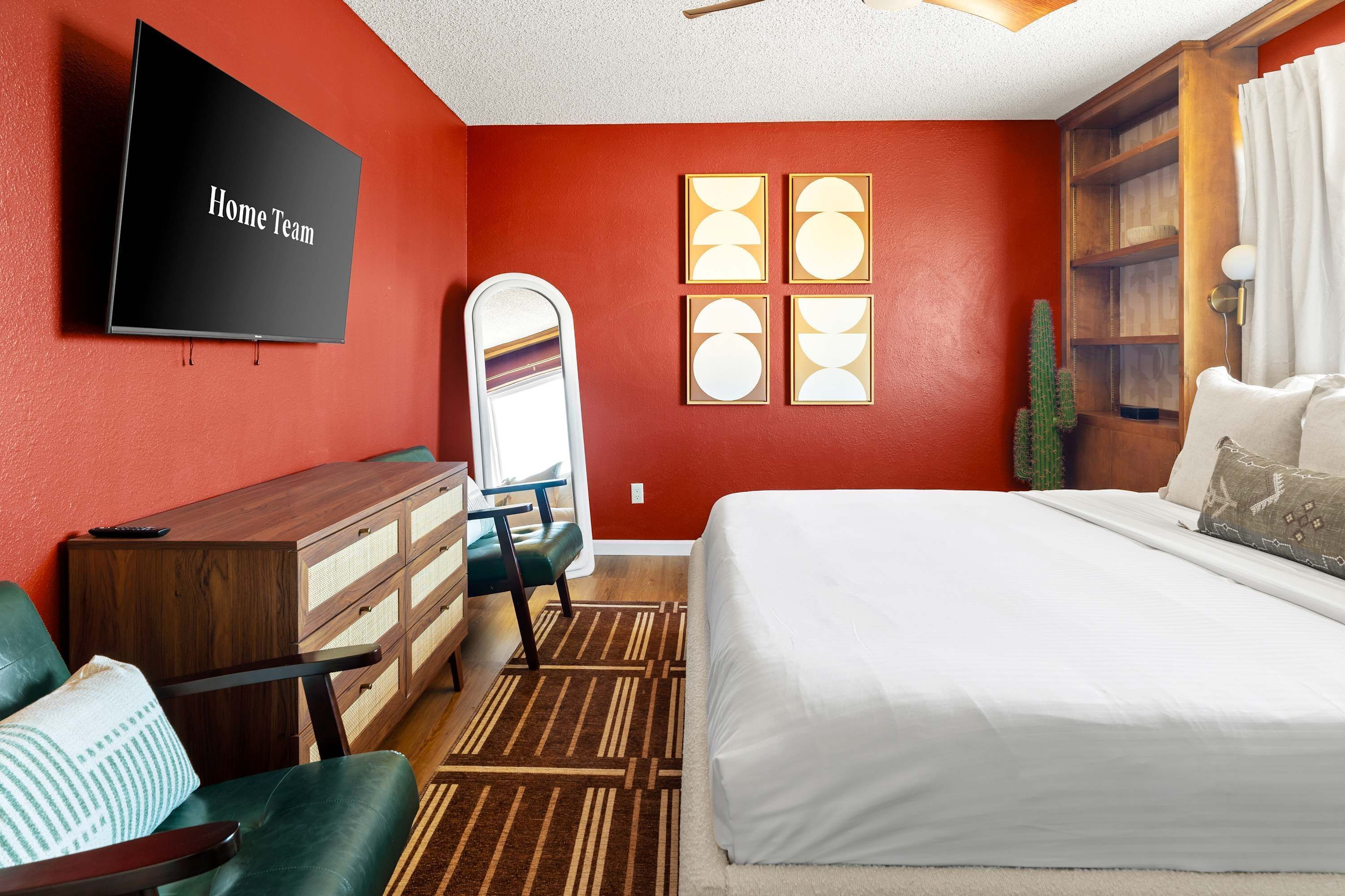 A hotel room with a large bed, a TV, a dresser, a chair, and a window with a view of the desert.