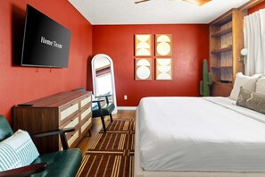 A hotel room with a large bed, a TV, a dresser, a chair, and a window with a view of the desert. - Epic Family Getaway Speakeasy Pool Basketball (Glendale)