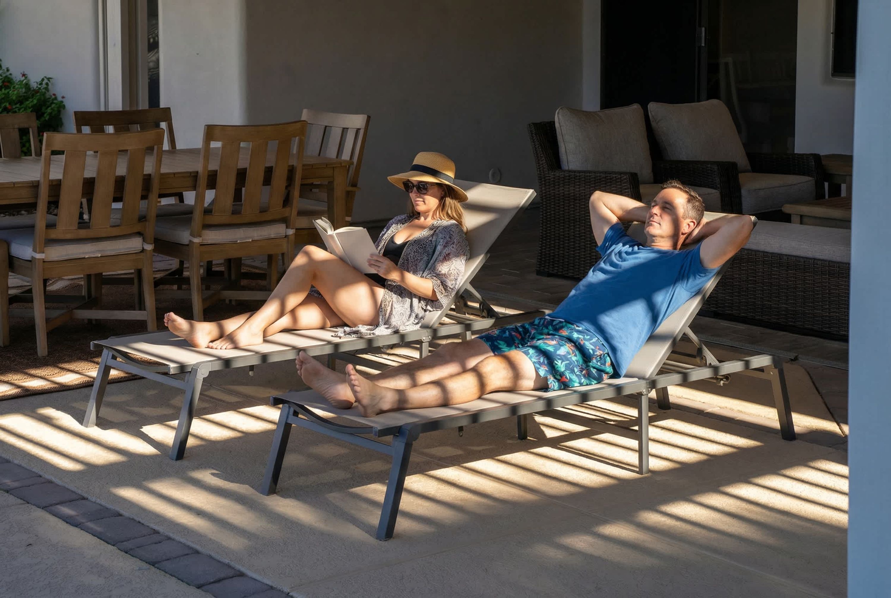 Deux fauteuils de jardin avec des structures métalliques et des coussins, placés sur une terrasse dont le sol est en béton.