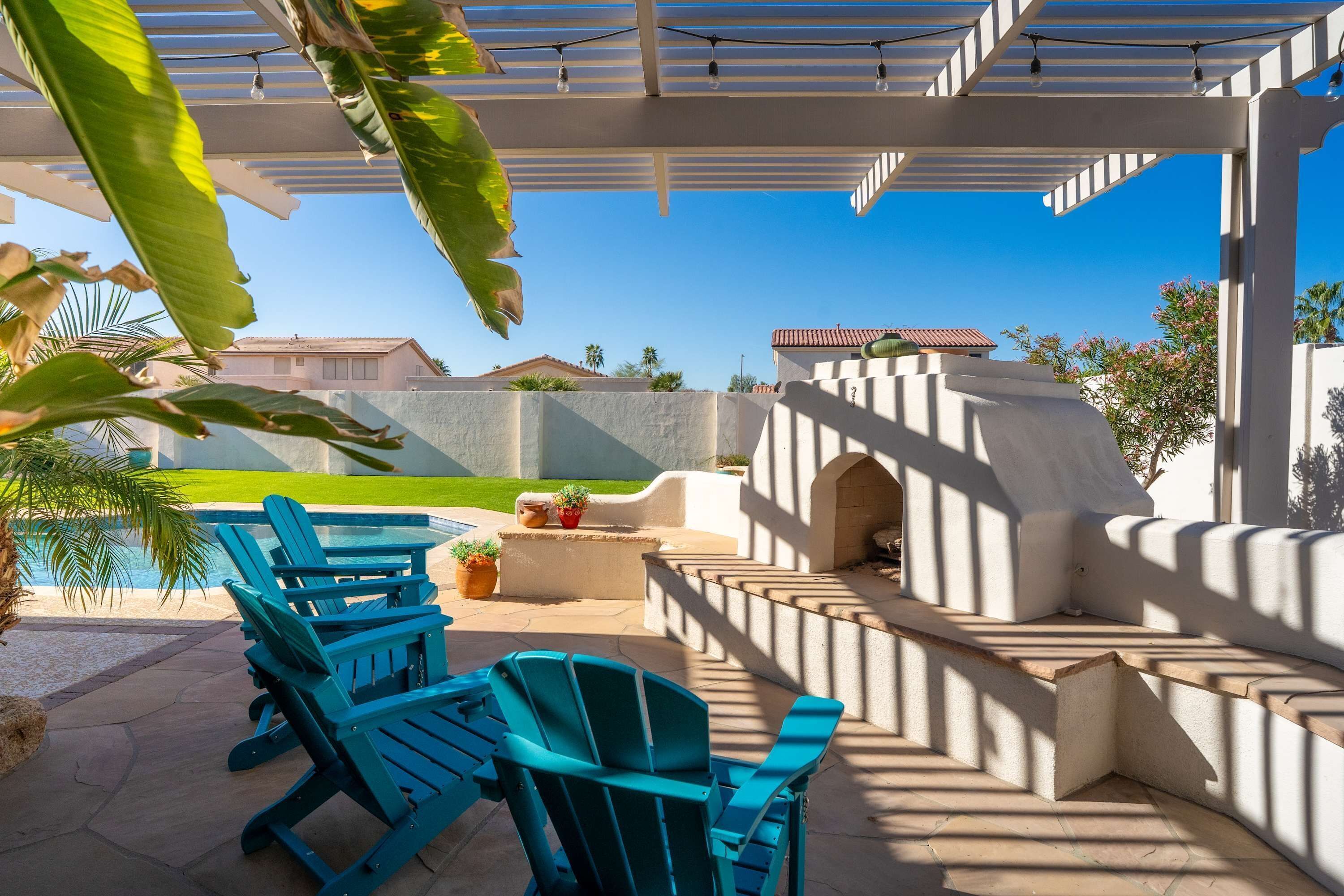 A covered outdoor area with a barbecue, seating, and a view of a residential neighborhood.