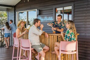 A bar area with a wooden exterior, a neon sign reading 'Stay Awhile', and a bamboo barrier. - Ocean Views Private Pool Walk to Beach (St. Augustine)