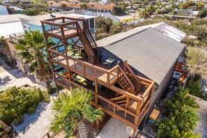 A multi-level wooden structure with outdoor seating and a pool, surrounded by palm trees and a residential area. - Ocean Views Private Pool Walk to Beach (St. Augustine)