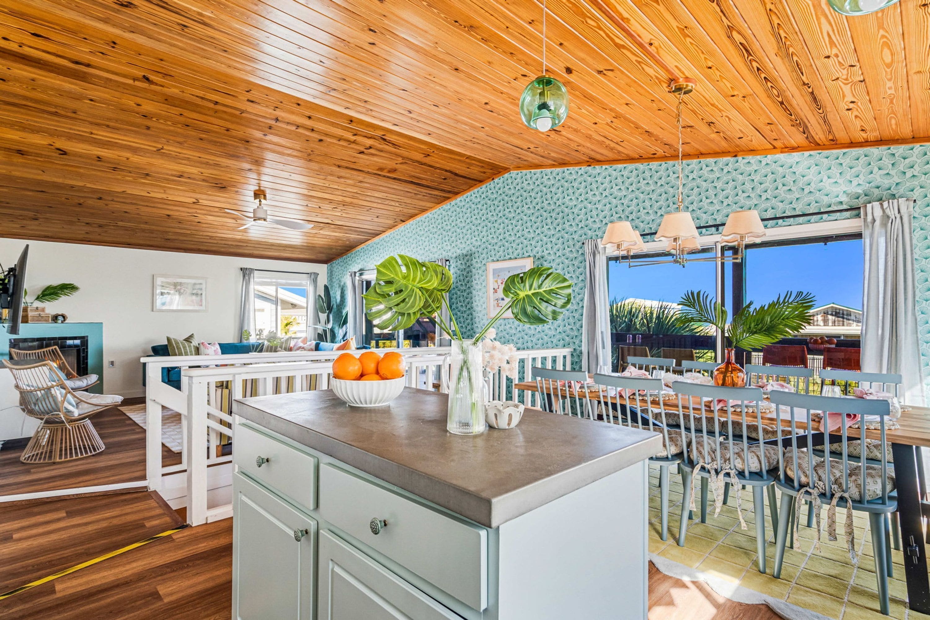 A kitchen with a wooden ceiling, a dining area with a table and chairs, and a view of the outdoors.