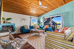 A living room with a wooden ceiling, a blue sofa, a striped sofa, a wicker chair, and a coffee table. - Ocean Views Private Pool Walk to Beach (St. Augustine)