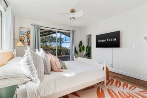Ein Schlafzimmer mit einem Bett, einem Deckenventilator, einem Fernseher und Blick ins Freie.